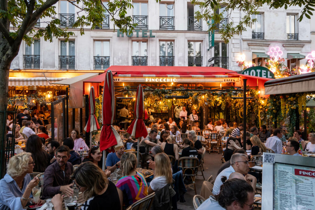 Bustling outdoor restaurant patio scene at twilight.